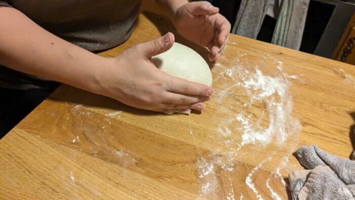 woman pulling a loaf of sourdough into itself