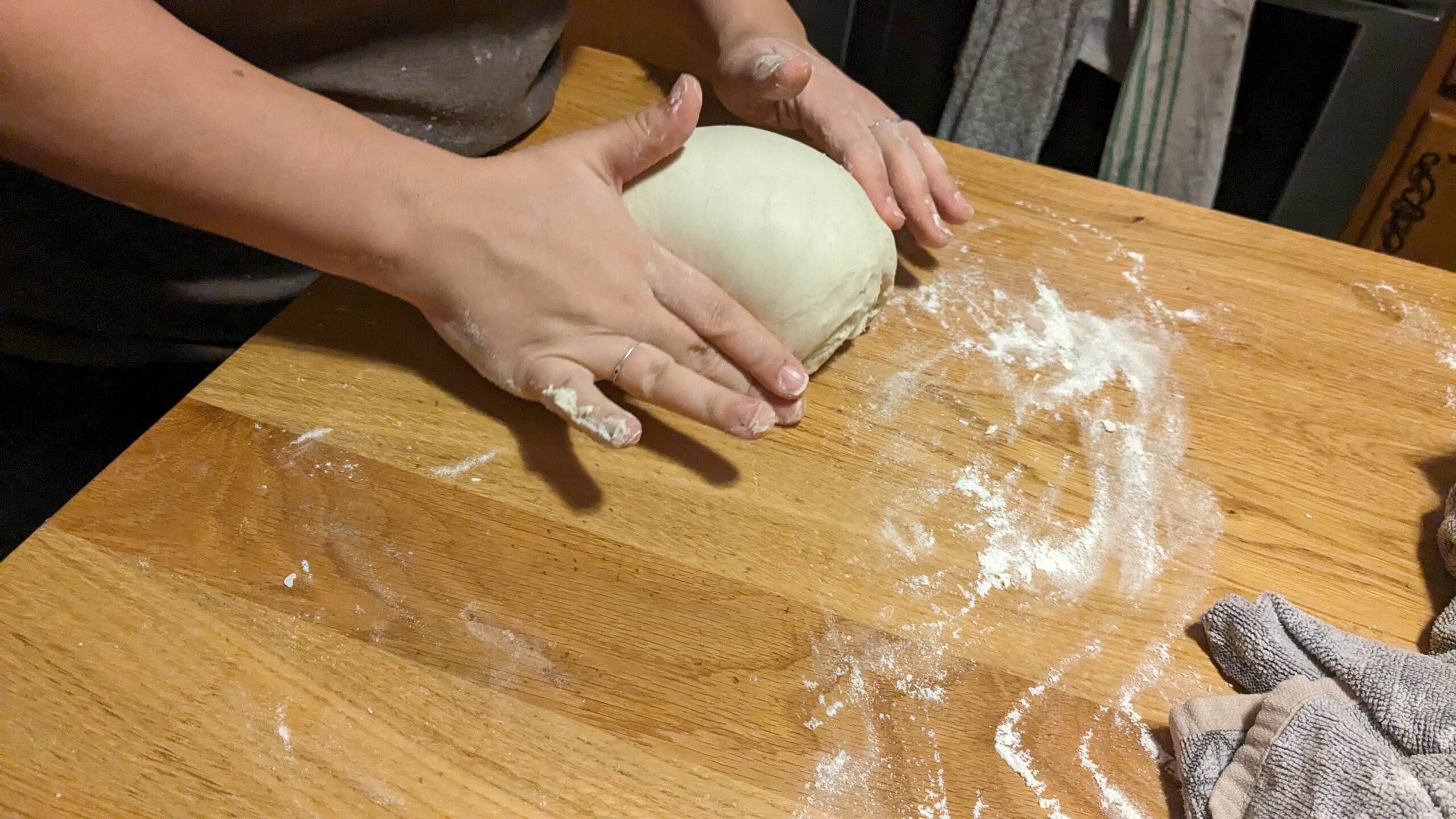 woman tucking and gently forming a sourdough loaf