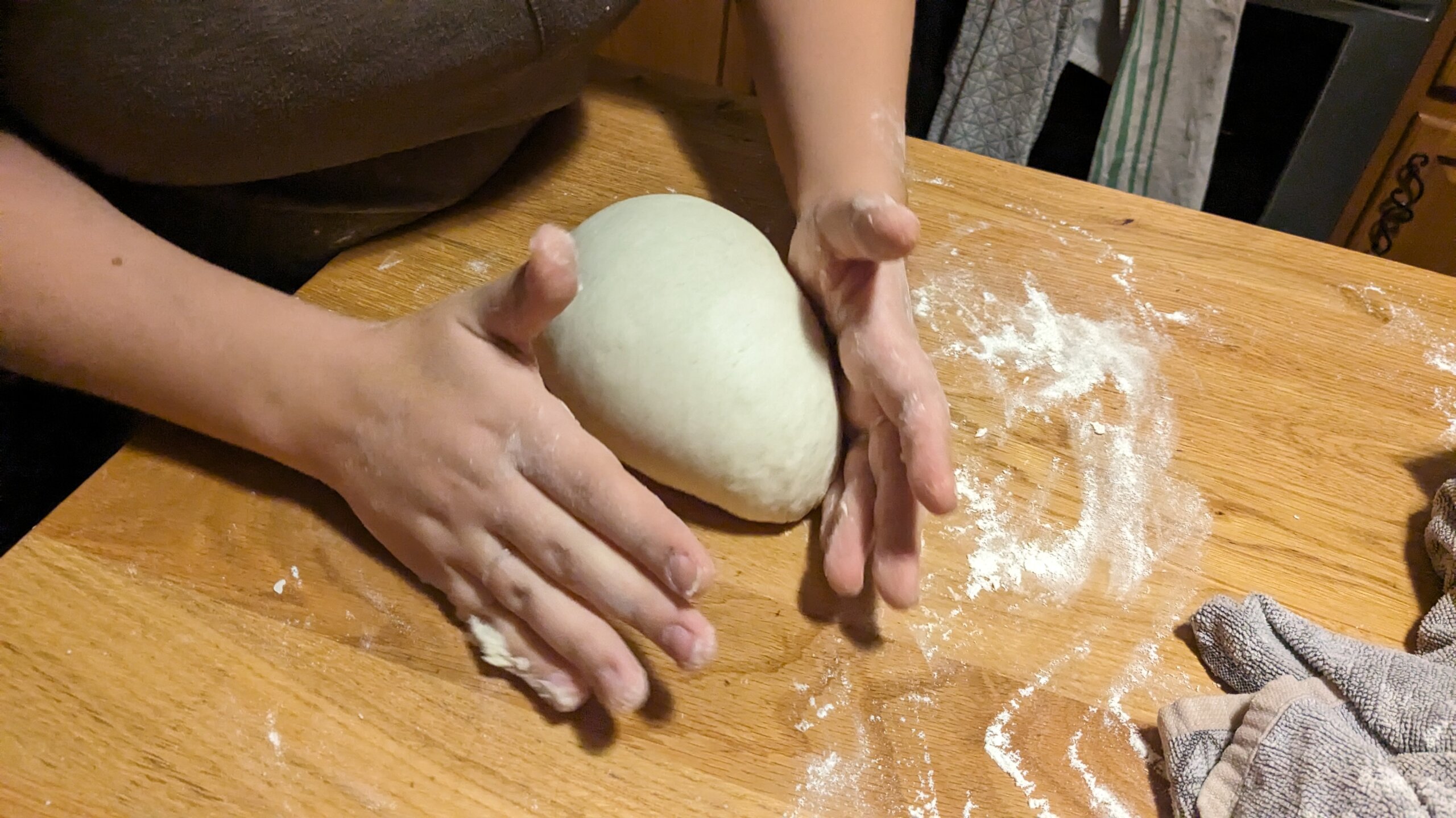 woman pushing a ball of dough into a loaf shape