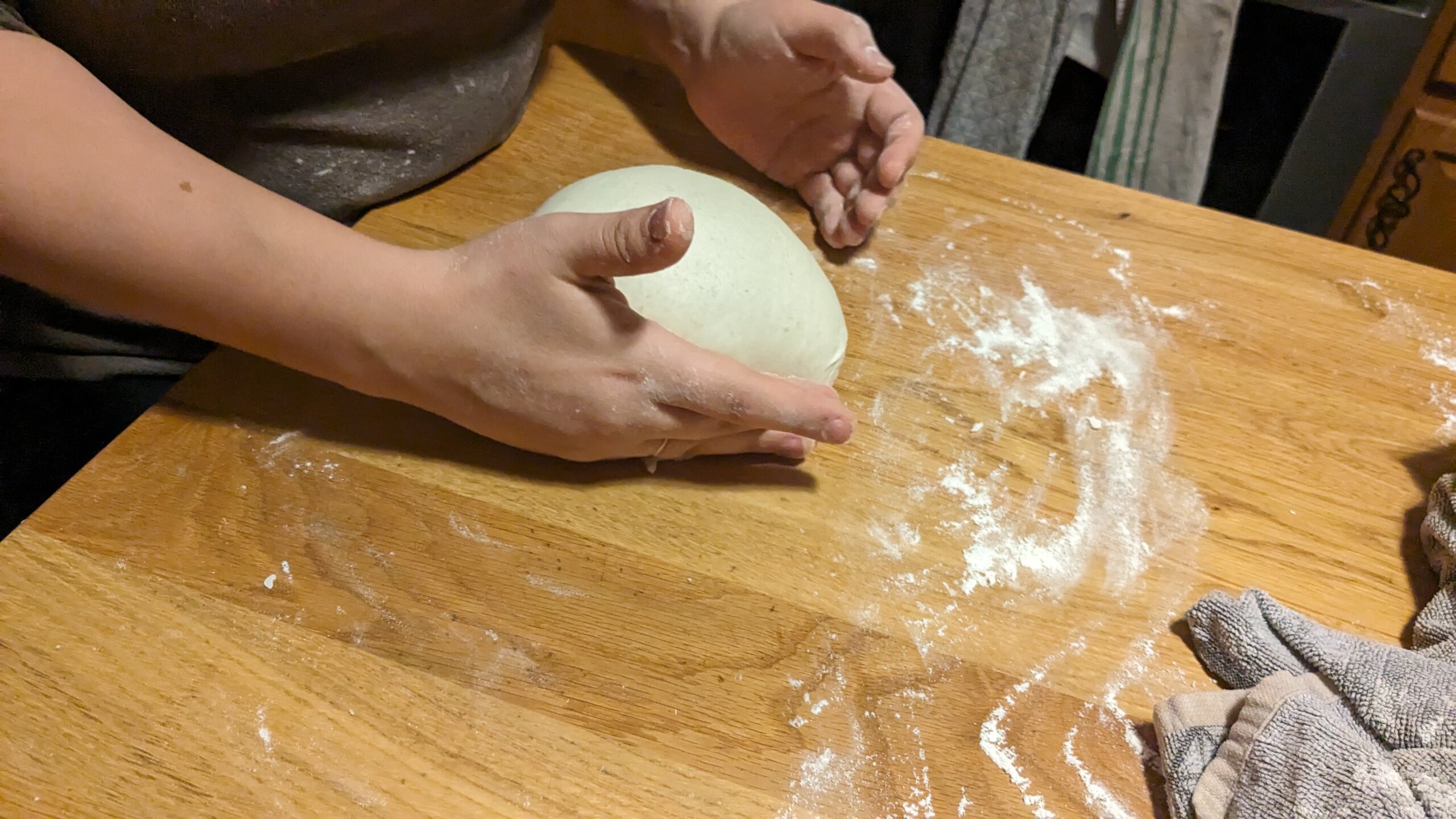 woman tucking a round sourdough loaf into itself