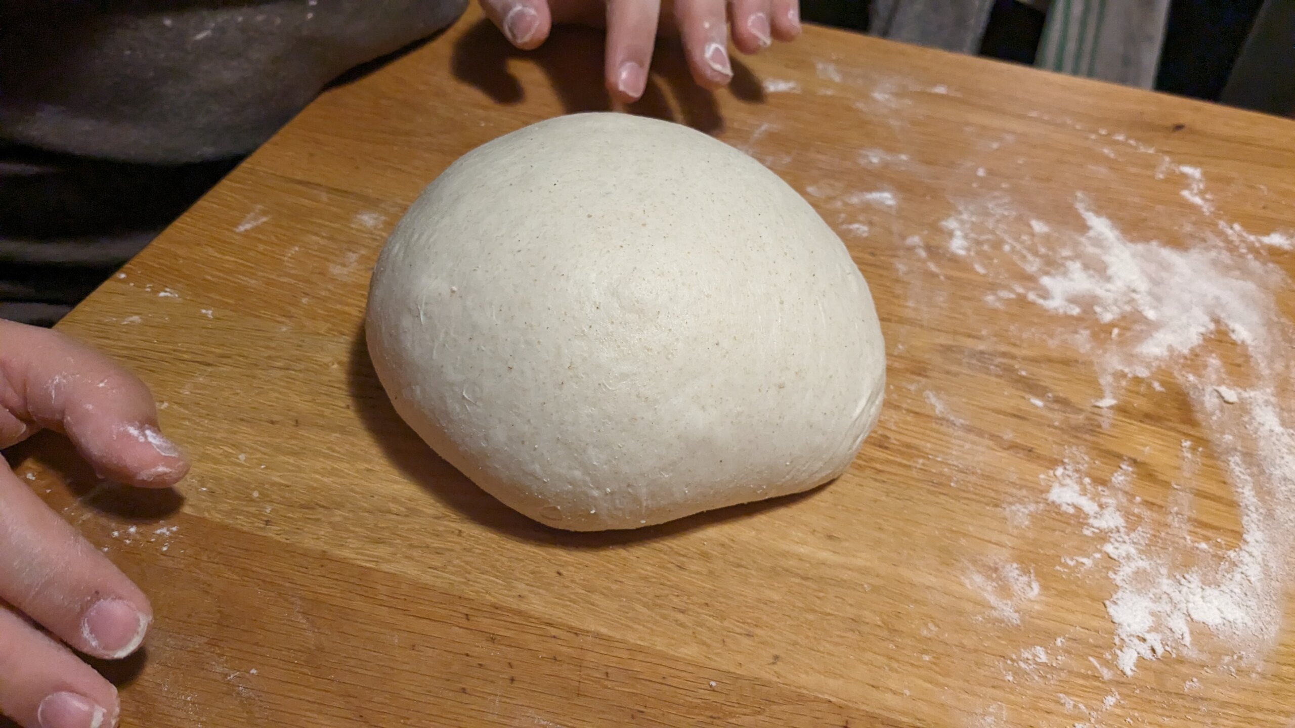 a round loaf of sourdough dough on a wooden counter