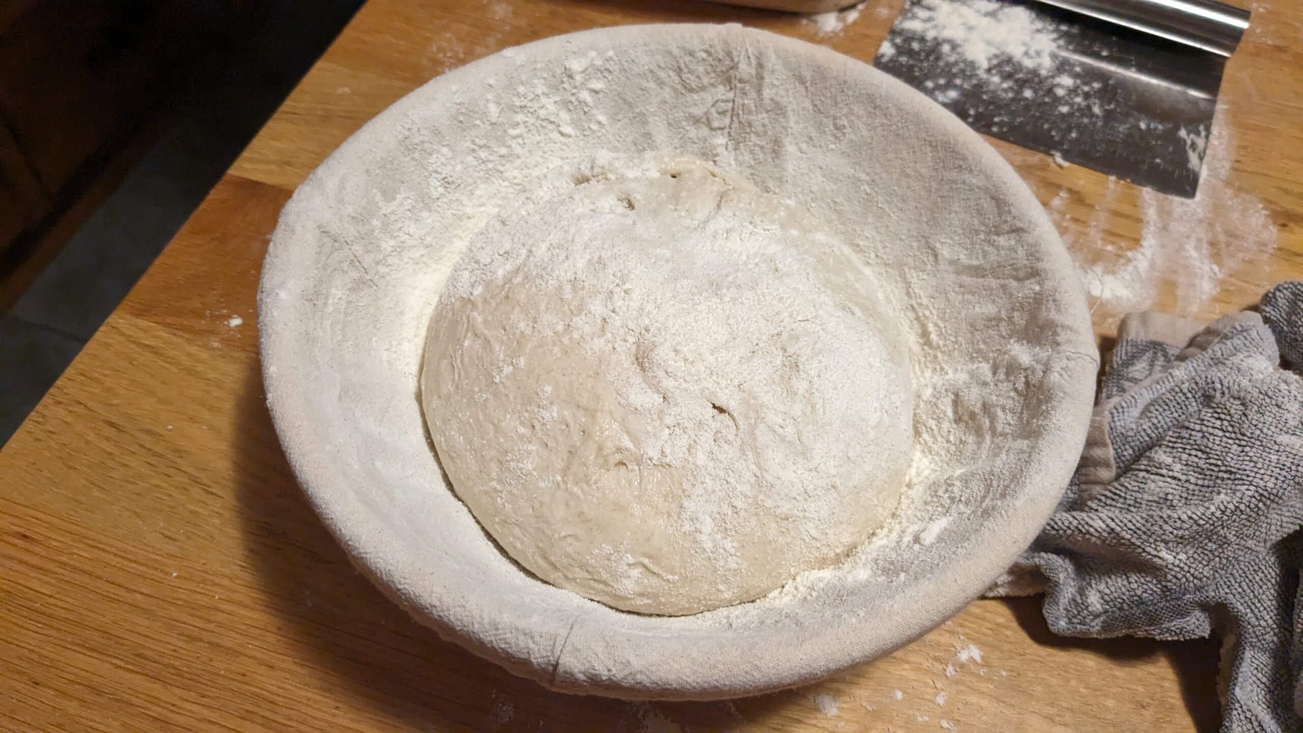 a sourdough boulle upside down in a floured banneton with flour on top