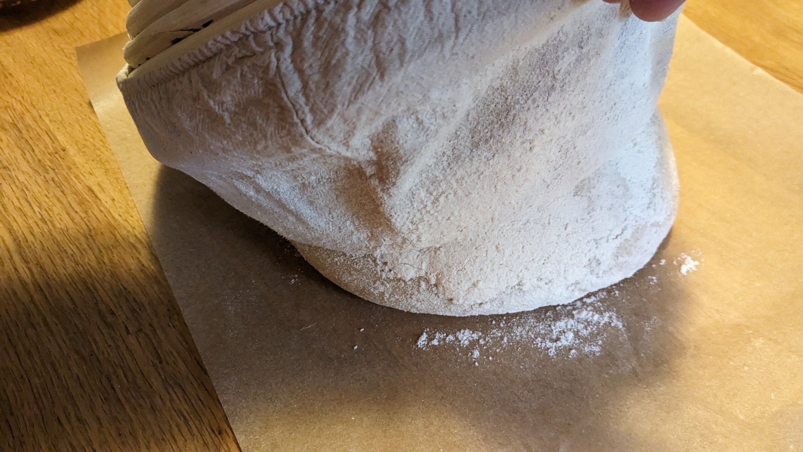 woman pulling a cloth banneton away from a sourdough dough ball