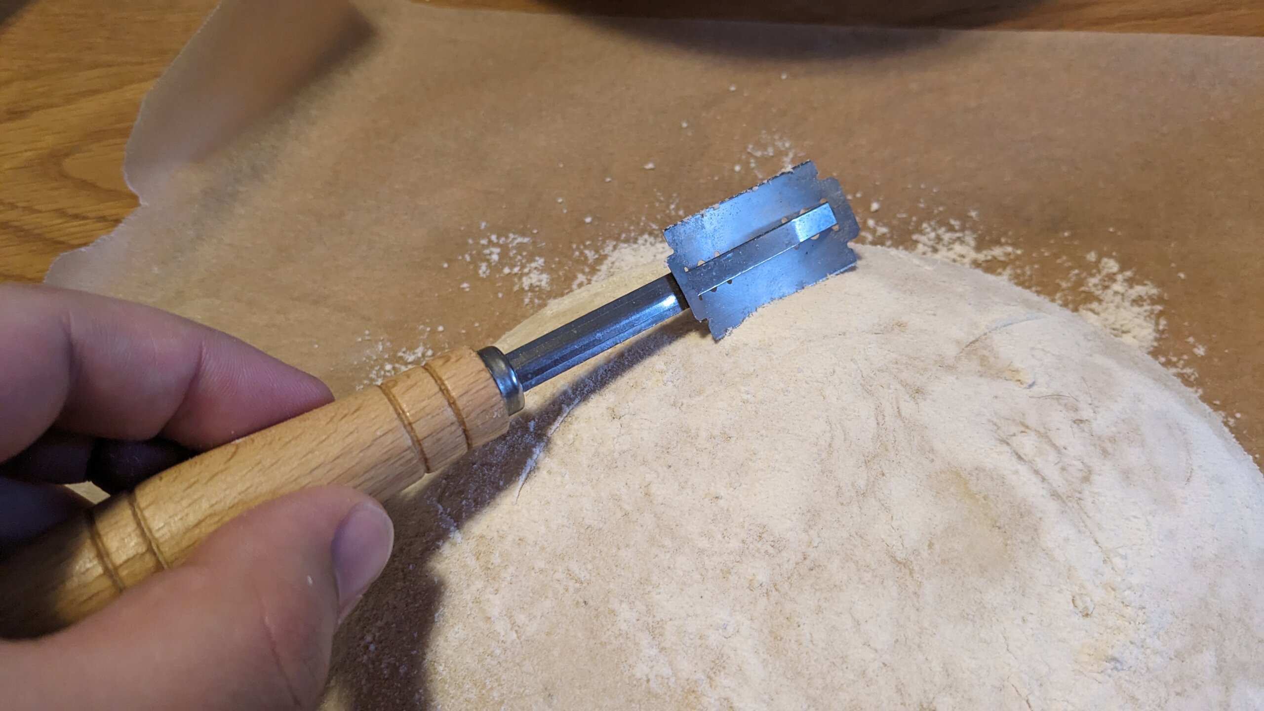 woman holding a lathe razor over a loaf of sourdough bread dough