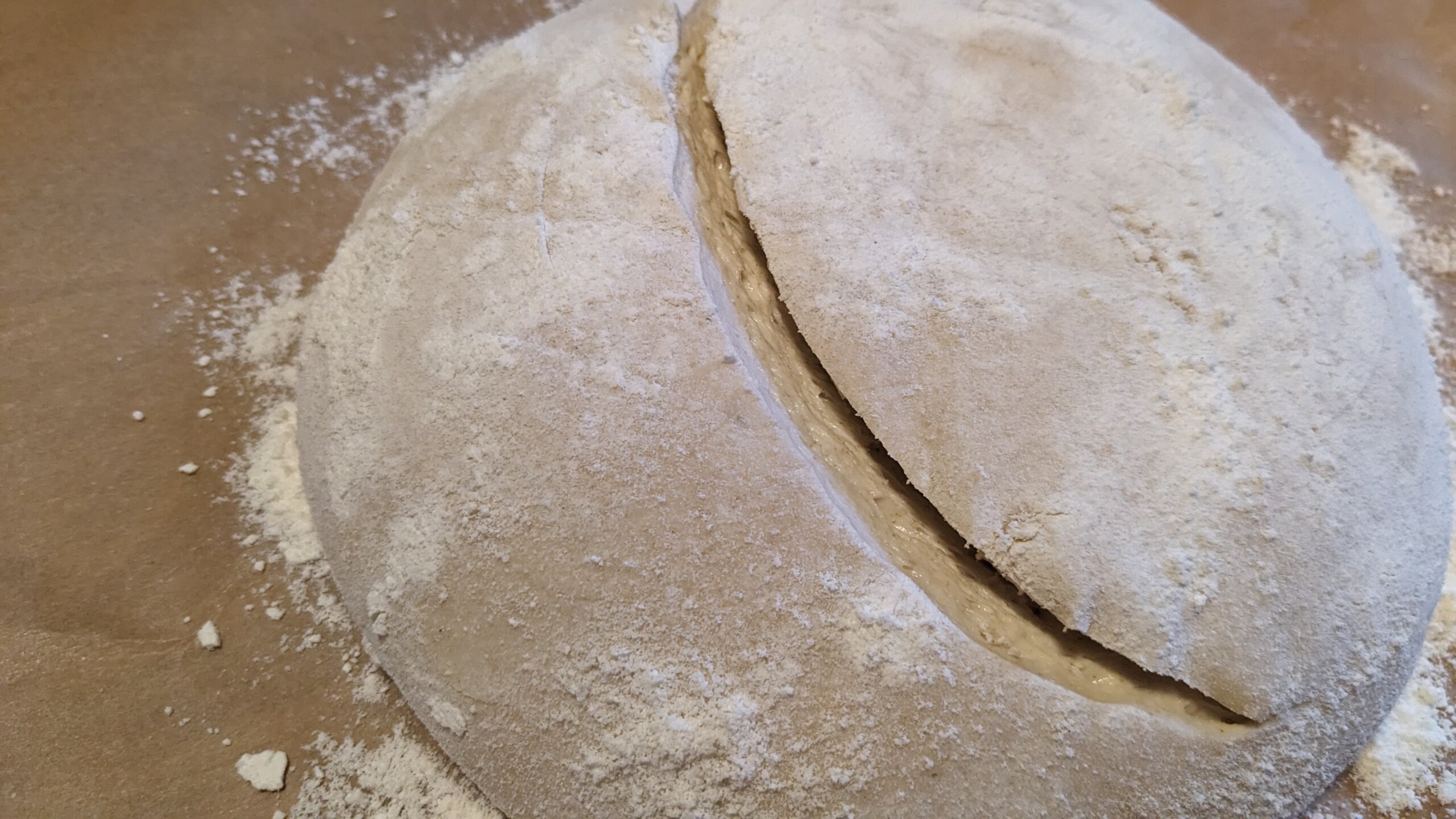 a loaf of artisan sourdough dough with a steam vent cut into in it