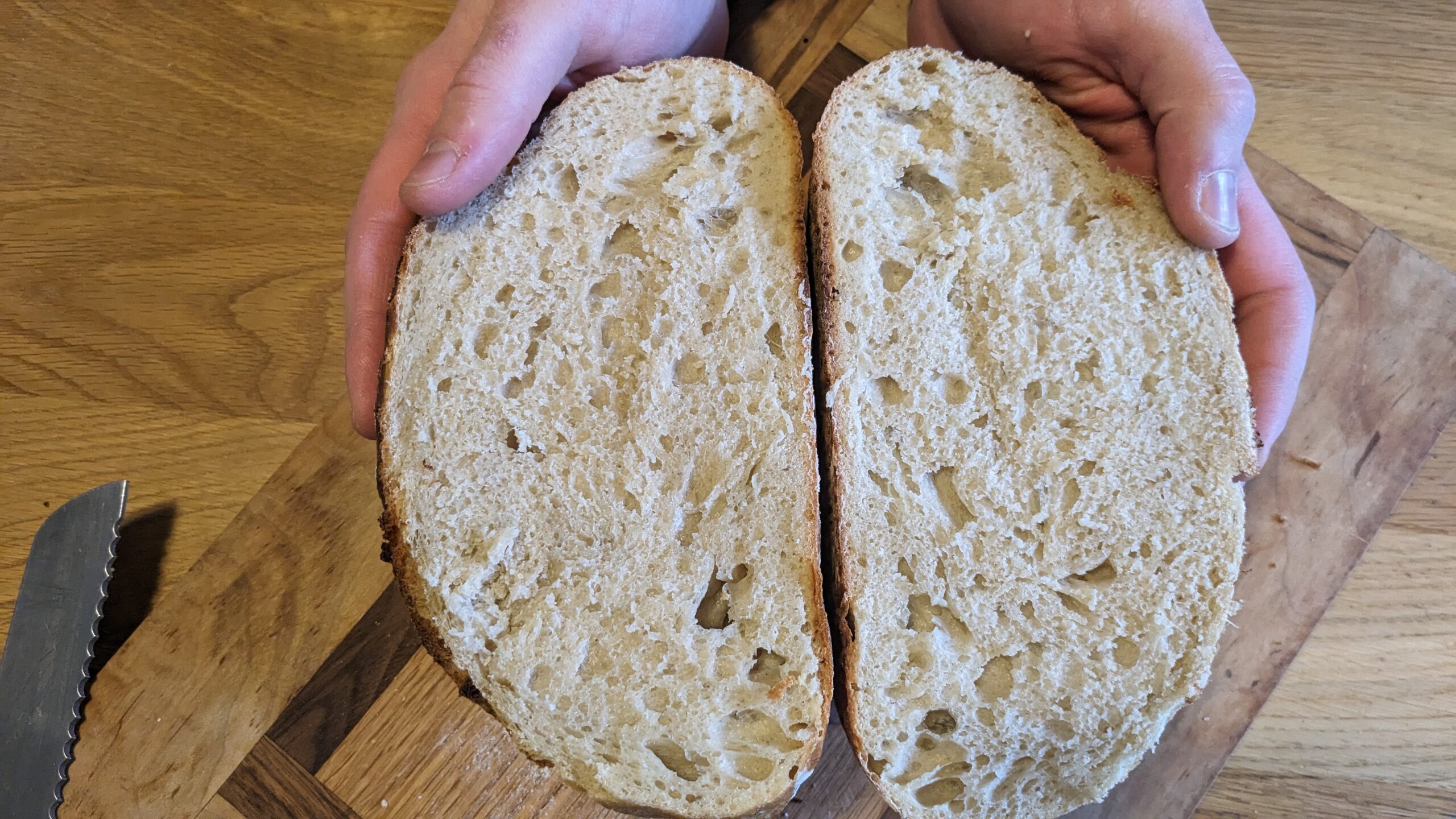 man holding two halves of an artisan sourdough loaf exposing the crumb