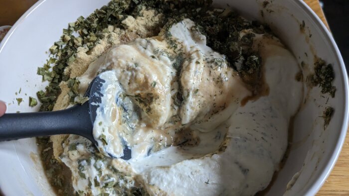 A spatula in a bowl of ingredients combing ranch dressing