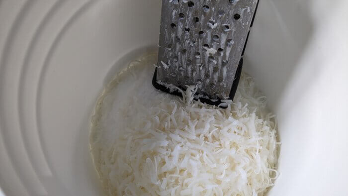 a box grater in a bucket of shredded white soap and white powder