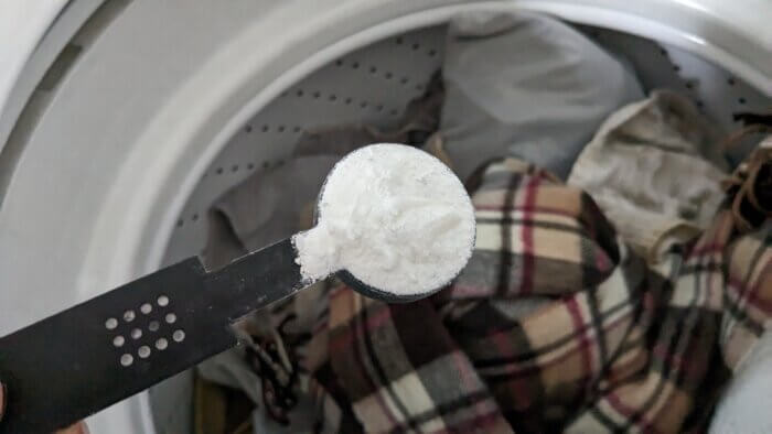 a tablespoon full of homemade powdered laundry detergent over a full washing machine