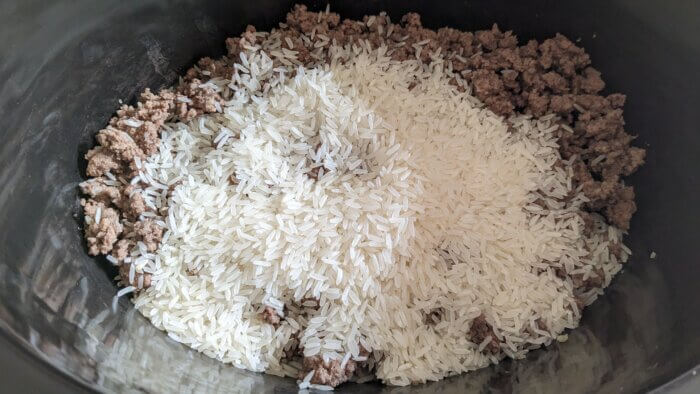 crock pot filled with cooked ground beef and uncooked rice