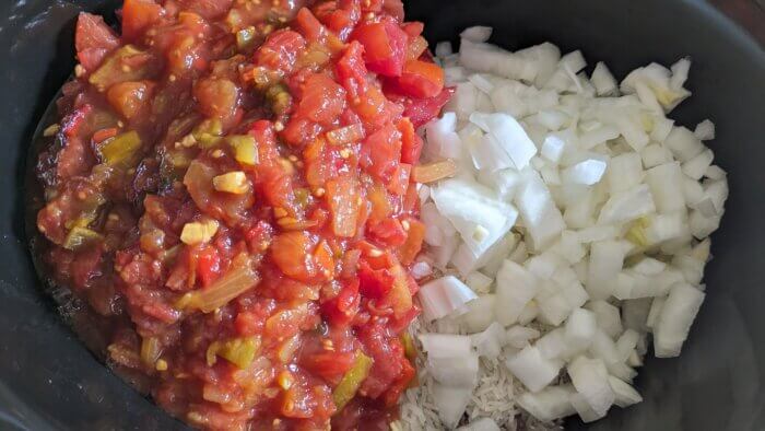 a crock pot with diced tomatoes and salsa and raw diced onions