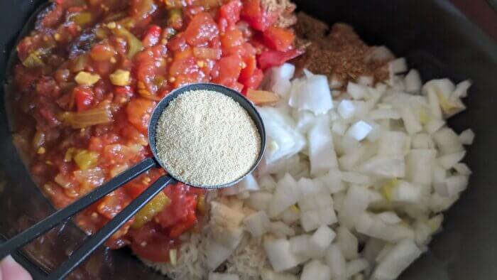 a crock-pot with diced tomatoes, diced, raw onions, and a tablespoon of garlic powder