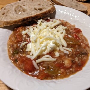 bowl of cowboy soup topped with greek yogurt and cheese with a slice of bread on top of the bowl