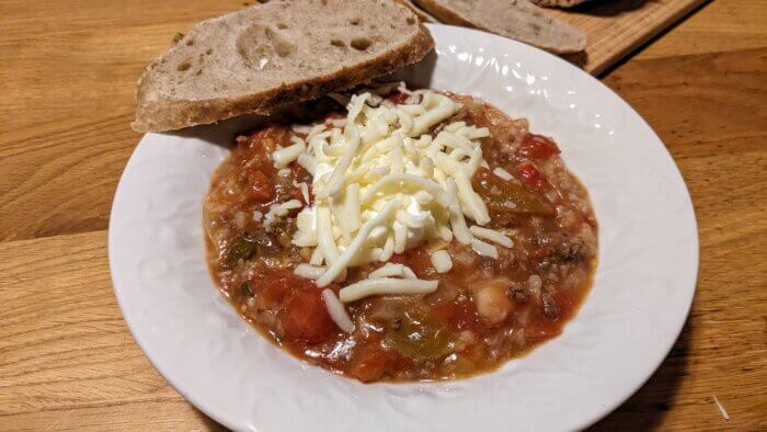 bowl of cowboy soup topped with greek yogurt and cheese with a slice of bread on top of the bowl