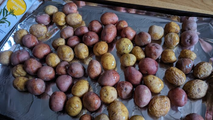 baby potatoes on a tinfoil lined tray next to a bottle of sesame oil