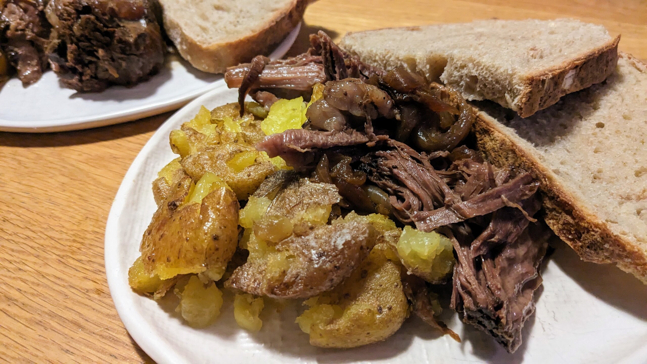 chinese pot roast on a plate with smashed potatoes and sliced sourdough bread