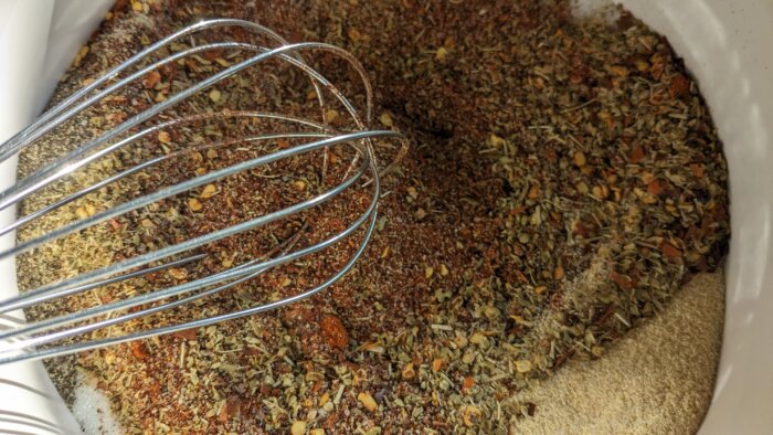 a whisk above a bowl of mixed spices