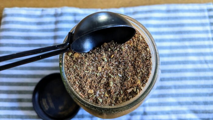 a tablespoon measurement above a jar of bulk homemade taco seasoning