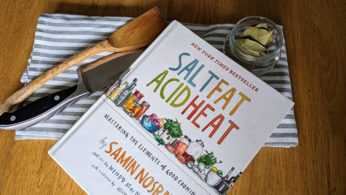 a cooking book next to kitchen utensils on a towel