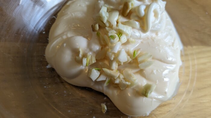 chopped garlic on mayonnaise in a glass bowl