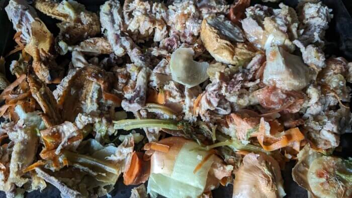 a tray of uncooked vegetable scraps and chicken bones