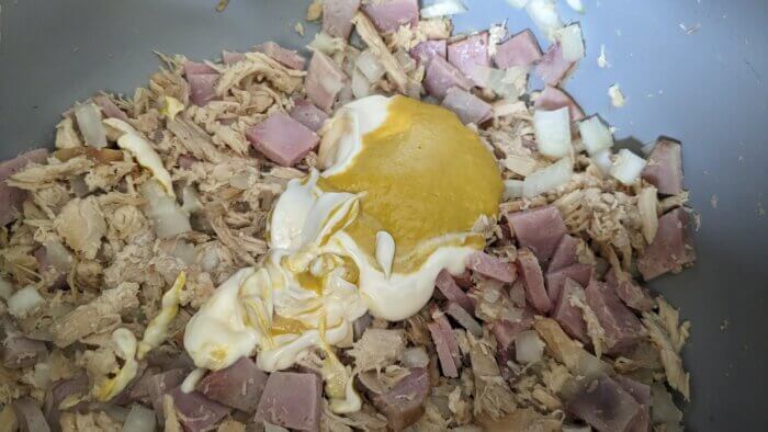 mustard and mayo on top of shredded chicken, onions, and ham