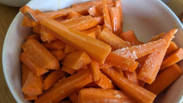 carrots sliced like fries in a bowl covered in oil and salt 