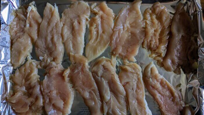 raw chicken tenders pounded thin on a tin foil lined pan