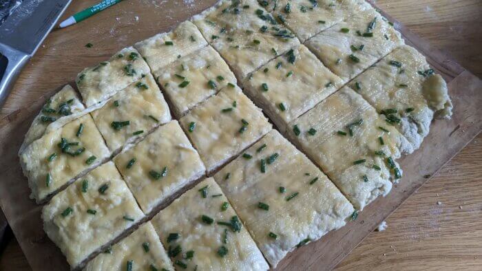 melted butter and herbs brushed onto sourdough Biscuit dough that has been cut into squares
