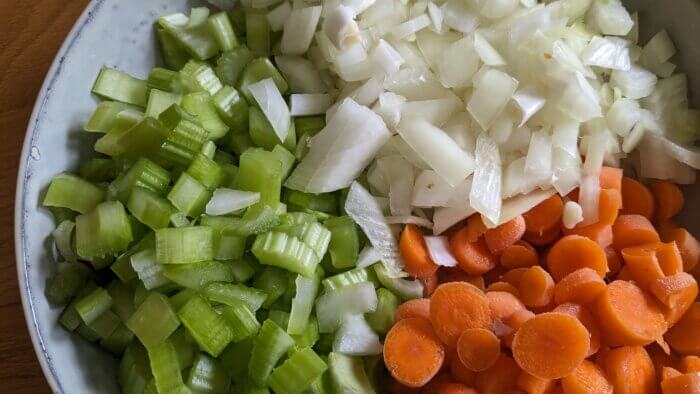 a bowl of raw diced onions, diced carrots, and diced celery