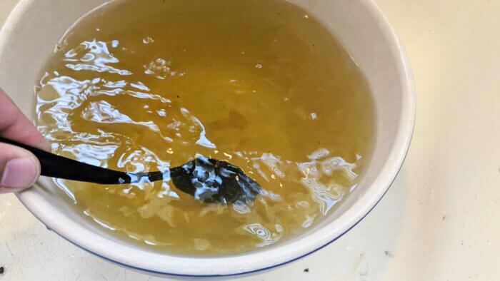 a spoon stirring honey into a bowl of mint tea