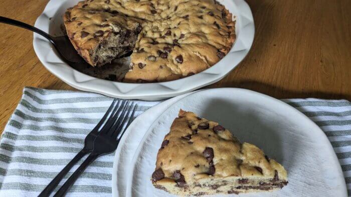 Close up of sourdough chocolate chip cookie pie next to a plate and forks