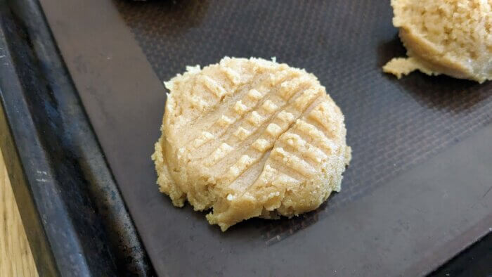 raw peanut butter cookie dough with a criss cross pattern made from a fork