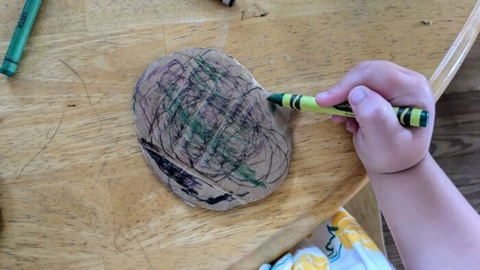 a toddler coloring a pumkin cardboard cutout