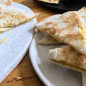 two plates of apple quesadillas next to a cutting board