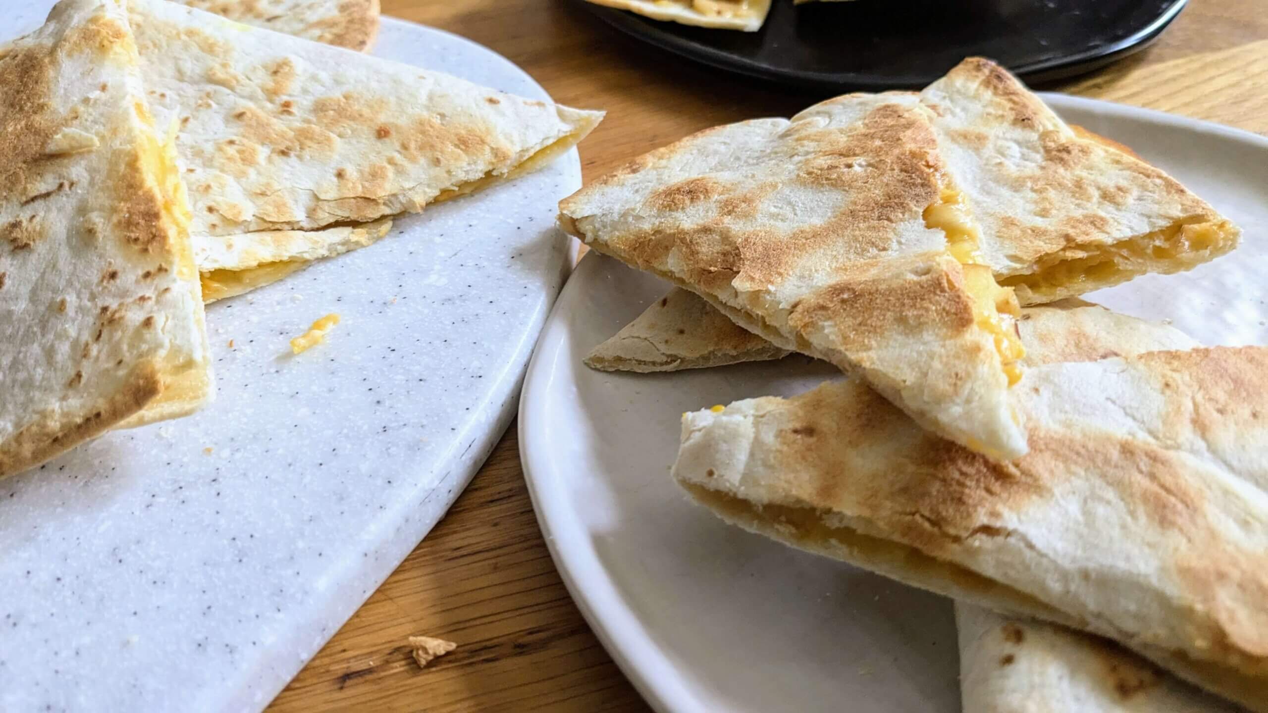 two plates of apple quesadillas next to a cutting board