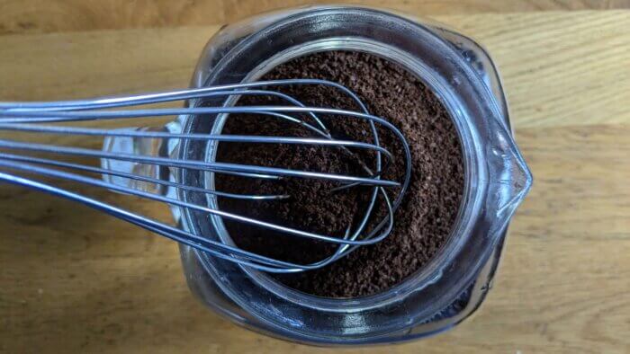 whisking coffee grounds into a pitcher of cold water