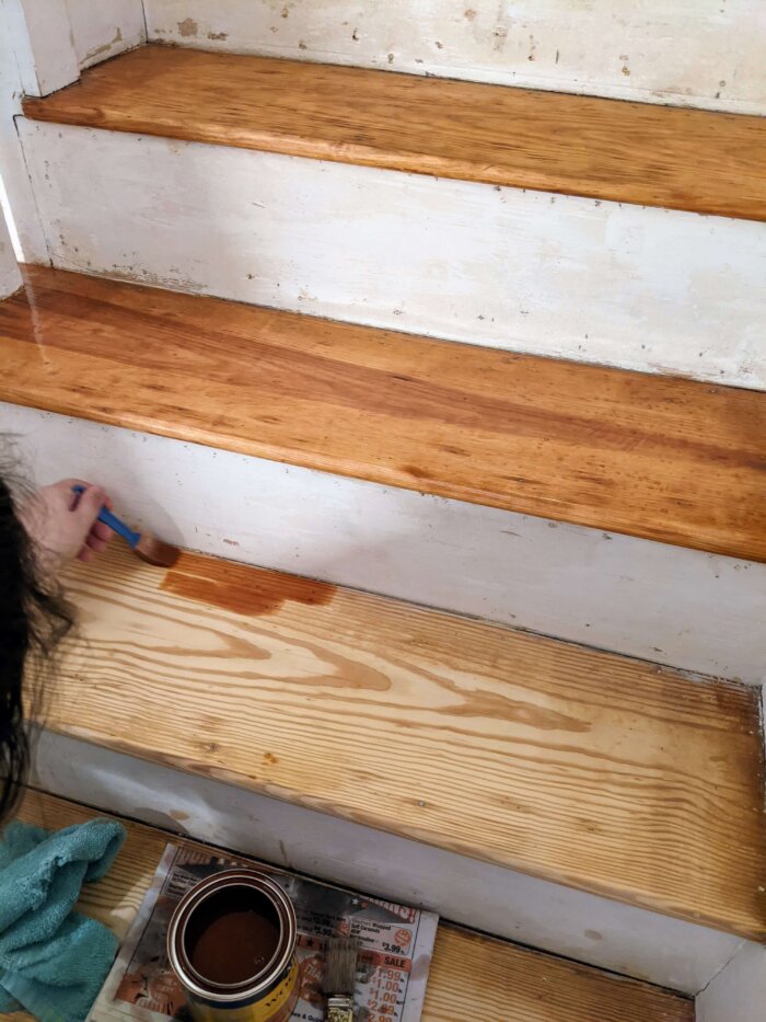 woman staining a raw staircase