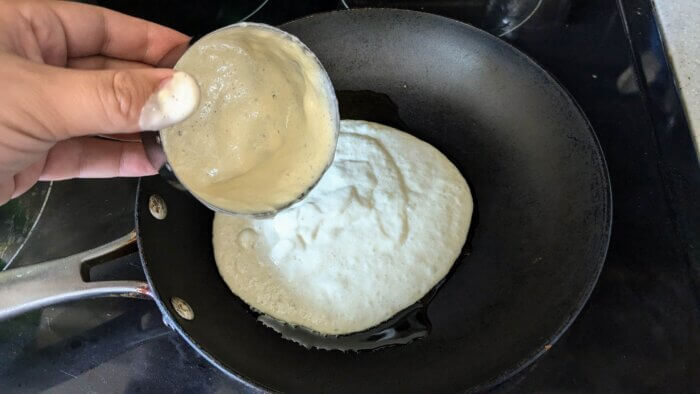 one cup of sourdough starter being poured into a skillet