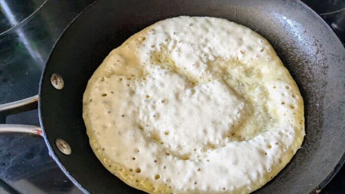 sourdough discard flatbread cooking in a skillet on a stove