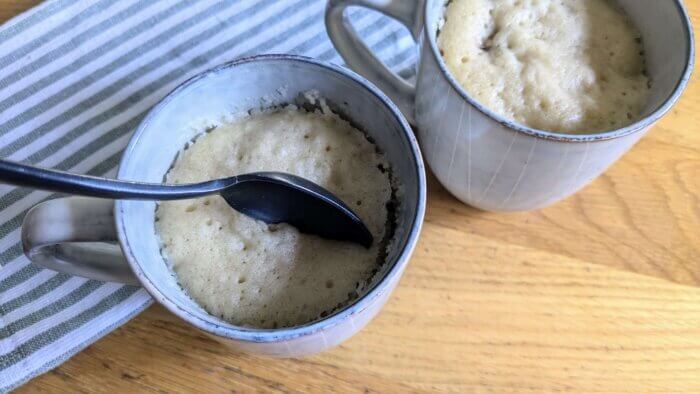 spoon in one of two sourdough chocolate chip mug cakes