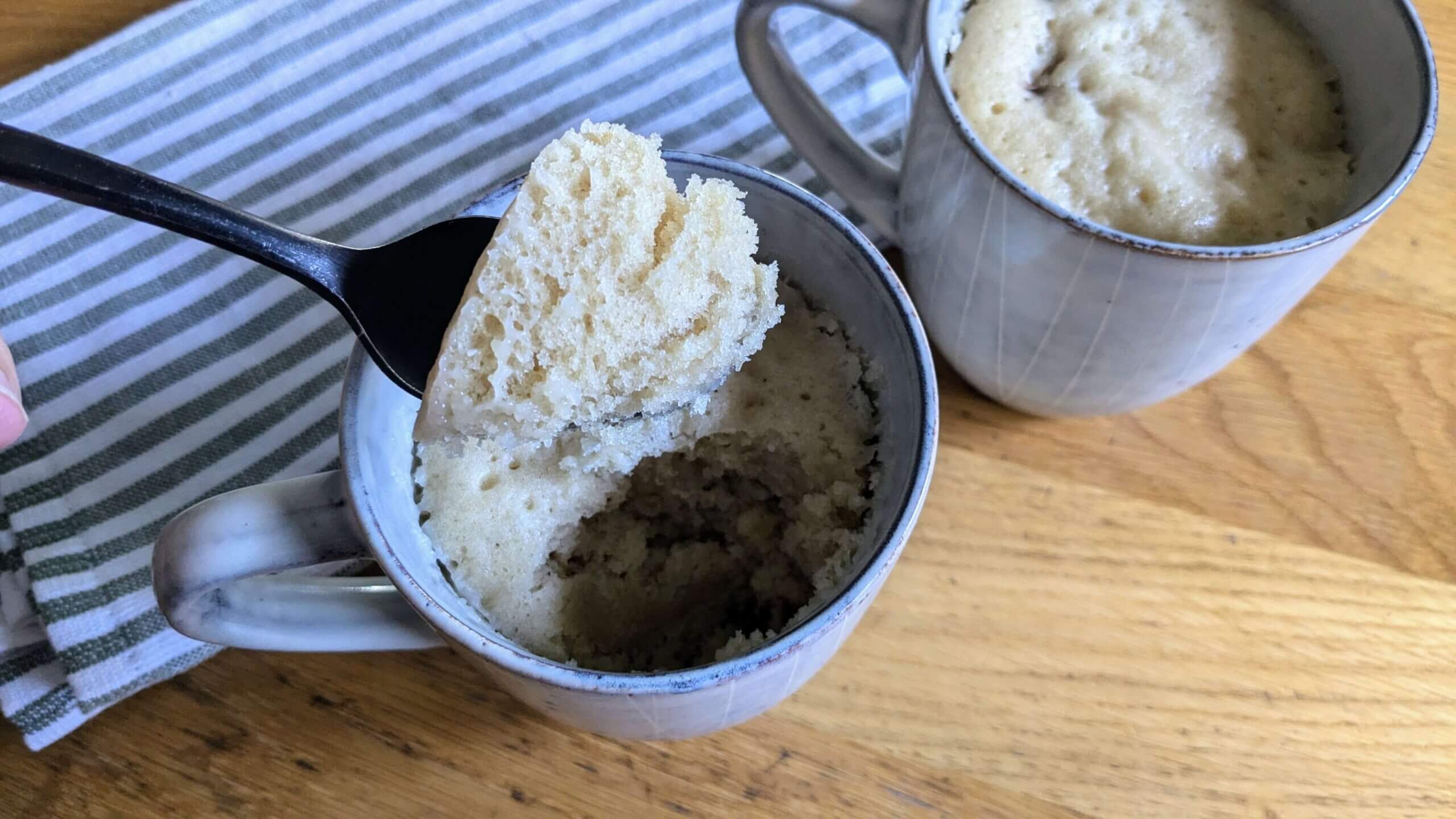 spoon in one of two sourdough chocolate chip mug cakes