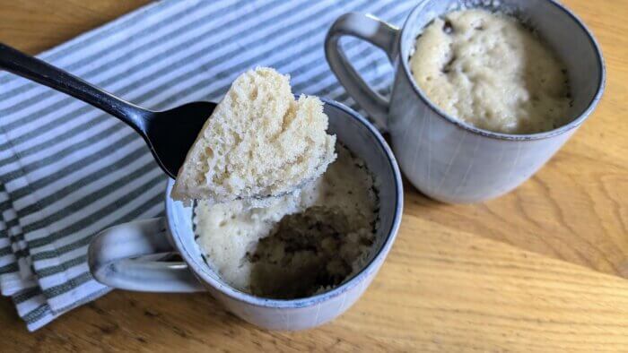 two mugs of cooked chocolate chip mug cake with a spoon