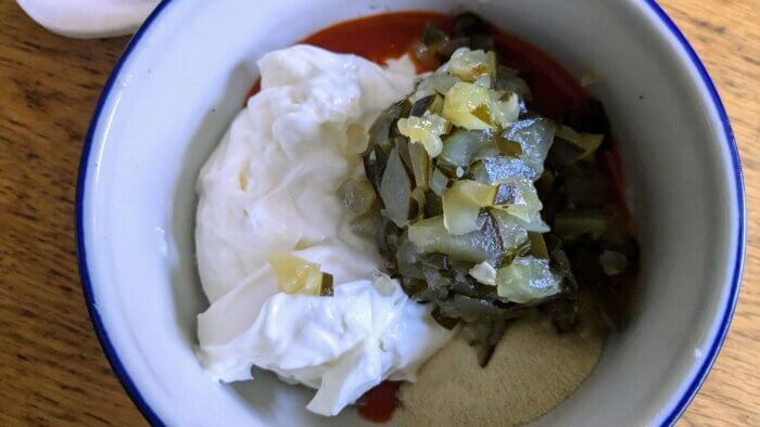 Chopped pickles, mayo, garlic powder, and hot sauce in a bowl