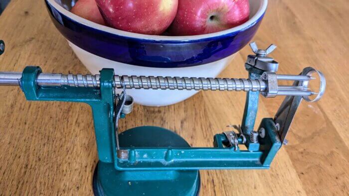 a bowl of apples behind a peeler/Corer/slicer