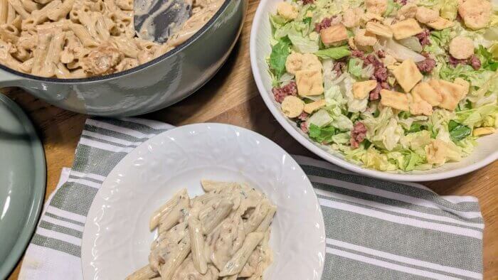 Garlic Parmesan Chicken Pasta in a bowl next to a large bowl of salad