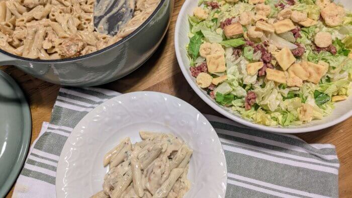 Garlic Parmesan Chicken Pasta in a bowl next to a large bowl of salad