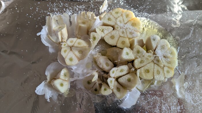 raw garlic drizzled with salt and olive oil on a piece of tin foil