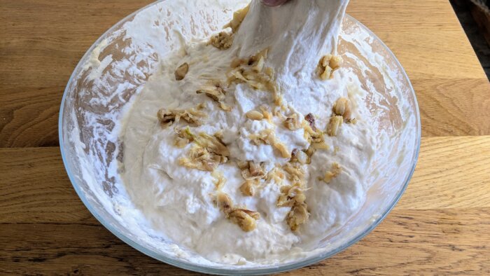 roasted garlic on top of sourdough dough being stretched and folded onto itself 