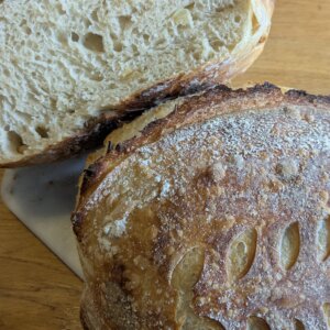 2 loaves of roasted garlic sourdough bread with one that has been cut resting on the other